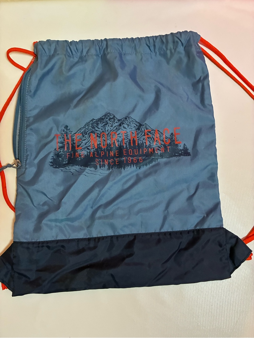 The North Face Light Blue Drawstring Bag with Orange Cord, Side Zip Pocket